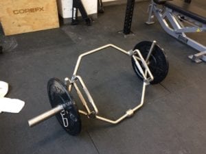 The hex bar gives a more straightforward (thus less taking on the body) "line of power" movement pathway than the standard deadlift with a barbell. Jaan Pill photo